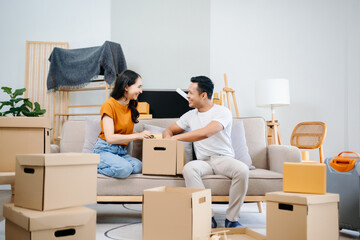 Asian young attractive couple man and woman use tablet and smartphone online shopping furniture decorate house with carton package move in new house. Young married asian moving home. .