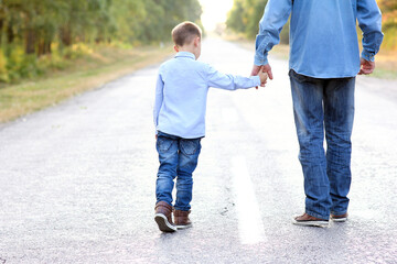 A Happy parent with a child  hands go along the road