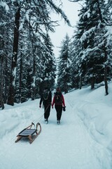 two people are hiking along the path carrying snow tools, and they are out in