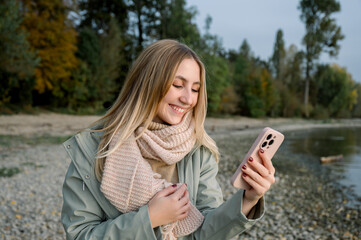 Smiling woman with smartphone near lake