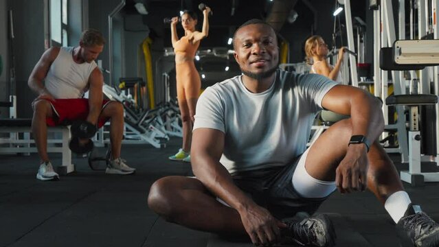 Black athletic man sits in confident pose resting after workout