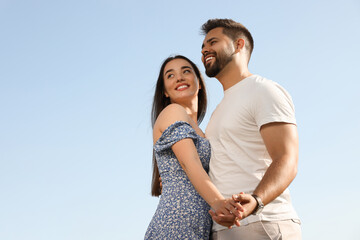 Romantic date. Beautiful couple spending time together against blue sky, low angle view with space for text