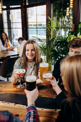Happy group of friends drinking and clinking with beer and cocktails at brewery bar restaurant