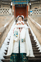 Fototapeta na wymiar After a heavy snowfall, beautiful women in ancient costumes are seen in the scenic area
