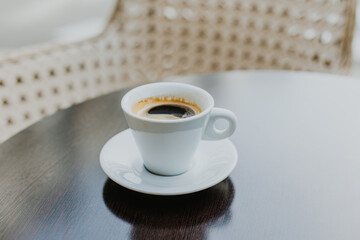 Cup of black coffee on a wooden table in a street cafe.