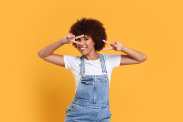 Happy young woman dancing on orange background