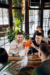 Happy group of friends drinking and clinking with beer and cocktails at brewery bar restaurant