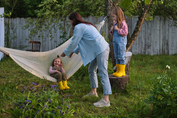 Heartwarming outdoor scene: A mother and her children cherishing simple pleasures, with laughter, hammocks, and nature as their backdrop