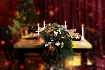 Christmas table setting for festive dinner, bokeh effect. Candles, garland, plates and glasses on table indoors
