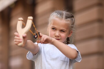 Little girl playing with slingshot on city street