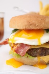 Delicious burger with fried egg on white table, closeup