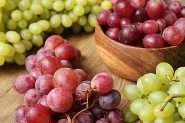 Different fresh ripe grapes on wooden table, closeup