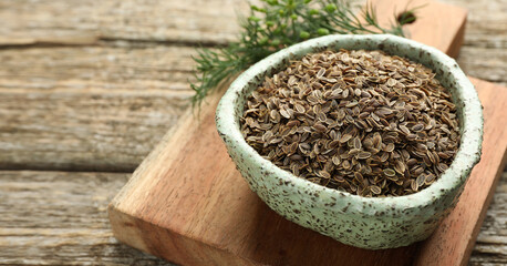 Dill seeds in bowl on wooden table, closeup. Banner design with space for text