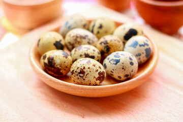 Quail eggs in a wooden bowl on a wooden background. Selective focus.