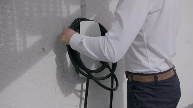 taking charging cable from the private wallbox to charge a Tesla
