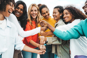 Multicultural group of women stacking hands together - Female community concept with different girls support each other - Girlfriends hugging outdoors - Powered by Adobe