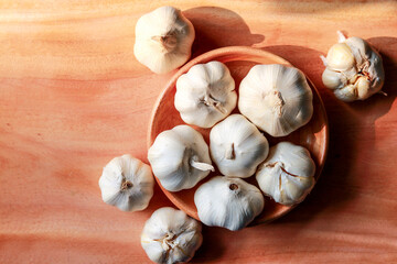 Garlic in wooden bowl on wooden background. Top view. Flat lay.