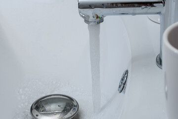 Odkręcony kran w umywalce w łazience, oszczędzać wodę 