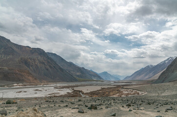 Valley between mountains on a cloudy day. A Dried river trains of Shyok river in Nubra Valley in...