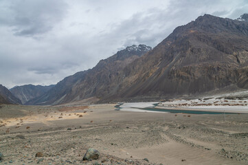 Valley between mountains on a cloudy day. A Dried river trains of Shyok river in Nubra Valley in...