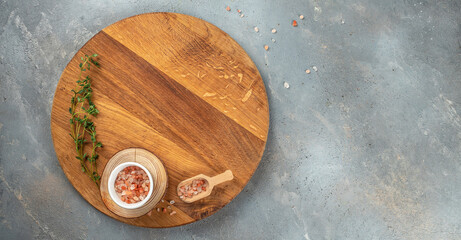 Empty wooden board on concrete table with cooking ingredients on a light background top view. place for text