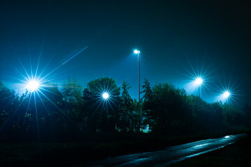 Light poles with bright lights near a sports field in the evening hours