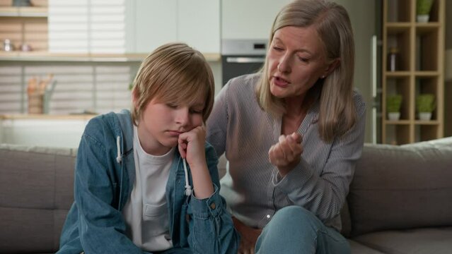 Strict angry elderly senior Caucasian woman grandmother punishing disobedient lazy offended grandson at home scolding grandchild kid boy due to bad behavior discipline family conflict explaining rules