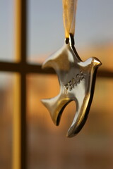 A Peace stamped bird ornament hangs by the window. Dusk background