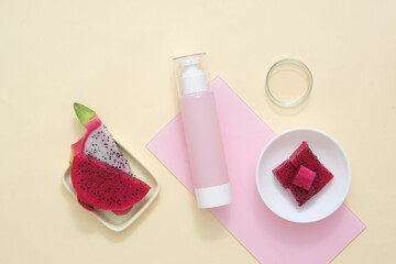 Set against a beige backdrop, an acrylic sheet, fresh dragon fruit, and carefully chosen props create a simulated scene for a vegan cosmetics ad featuring dragon fruit extract.