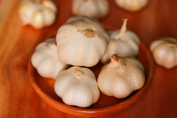 Garlic in a wooden bowl on a wooden background. Close-up.