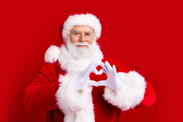 Photo of kind cheerful pensioner saint nicholas showing you heart shape isolated on red color background