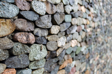 Wall made of medium sized colored oval stones, designer style, pebble fence, close-up