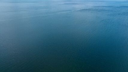Aerial view of the blue waters of the Mediterranean Sea and specifically the Tyrrhenian Sea. Sunlight reflects on the surface of the water.