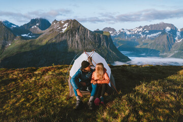 Couple friends traveling together with camping tent gear romantic vacations man and woman hiking adventure outdoor family healthy lifestyle explore mountains of Norway - obrazy, fototapety, plakaty