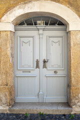 Wooden ornate arched entrance door to the building set in a stone wall.