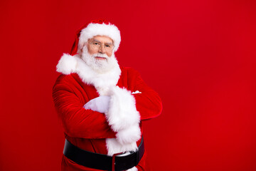 Photo of retired cheerful santa claus wear folded arms presenting empty space christmas magic dream isolated on red color background
