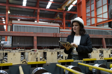 Female factory worker working and using digital tablet inspecting quality of production line conveyor in industry factory. Female inspector checking manufacturing process in plant