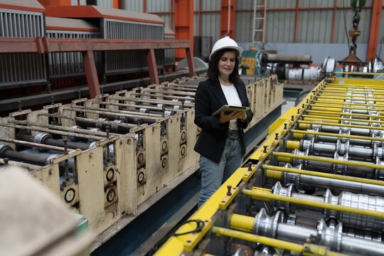Female factory worker working and using digital tablet inspecting quality of production line conveyor in industry factory. Female inspector checking manufacturing process in plant