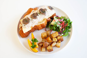 Mushroom cream cheese and scrambled egg brioche croissant sandwich with peach, rocket leaves feta cheese and sautéed potatoes.