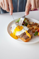 Breakfast egg and roast beef open faced sandwich served at a cafe restaurant.