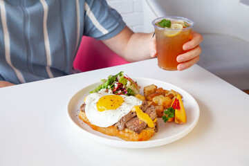 Breakfast egg and roast beef open faced sandwich served at a cafe restaurant.