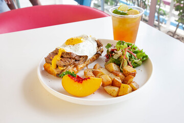 Breakfast egg and roast beef open faced sandwich served at a cafe restaurant.