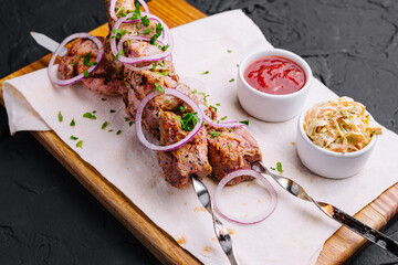 Juicy kebabs from pork on skewers laid out on a decorative board