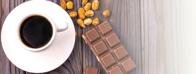 mug of coffee and chocolate with nuts on a wooden surface on sunlight