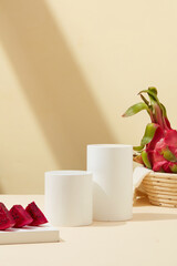 Cylindrical podium for product display, red dragon fruit displayed on a pastel background with shadows. Food and cosmetics containing fresh dragon fruit.
