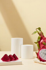 Few slices of red dragon fruit placed on a white podium and props. Mockup of skin care branding design of Dragon fruit (Hylocereus) extract.