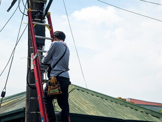 A technician troubleshoots a faulty internet fiber connection to a residence. Climbing up to check...