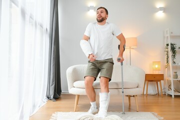 Recovery after physical injury in accident at home: Sad unlucky young man with broken leg, injured...