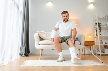 Recovery after physical injury in accident at home: Sad unlucky young man with broken leg, injured...