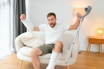 Happy man recovery from accident fracture broken bone injury with leg and arm. Social security and...